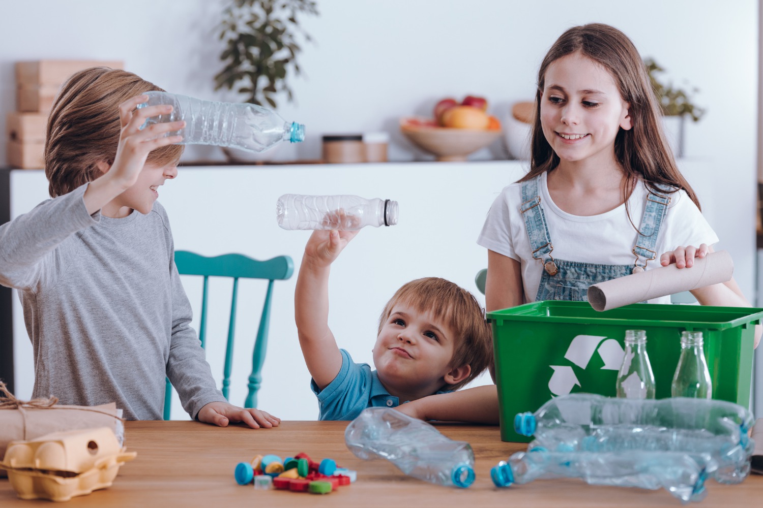 Dei bambini si divertono a riciclare delle bottiglie di plastica